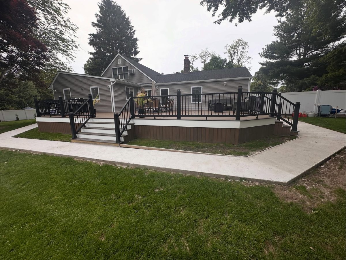 Rear home addition with a raised deck and patio on a Long Island ranch