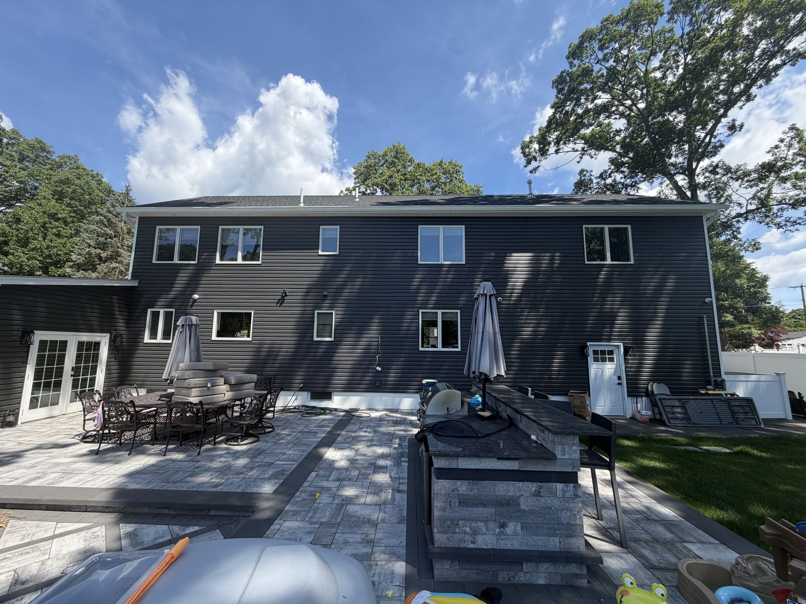 Rear view of a completed second-story addition with a paver patio on a Long Island home